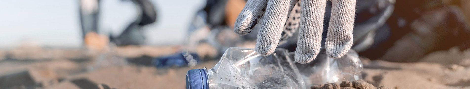 Hand, die eine weggeworfene Plastikflasche aufhebt